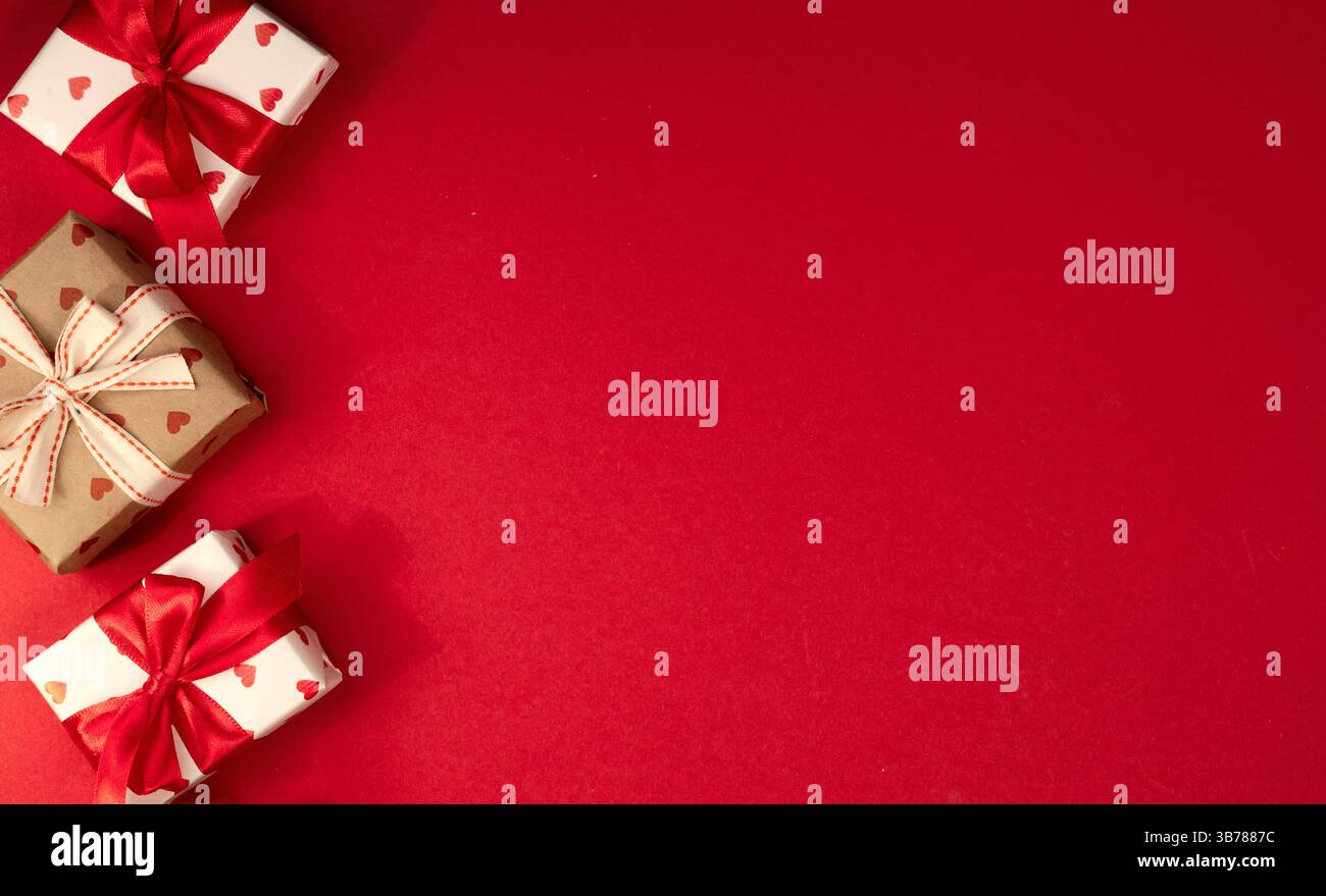 Vue de dessus des boîtes cadeaux sur fond d'espace vide rouge, toile de fond de saint-valentin, bannière de Noël, cadeaux attachés avec arc. Banque D'Images