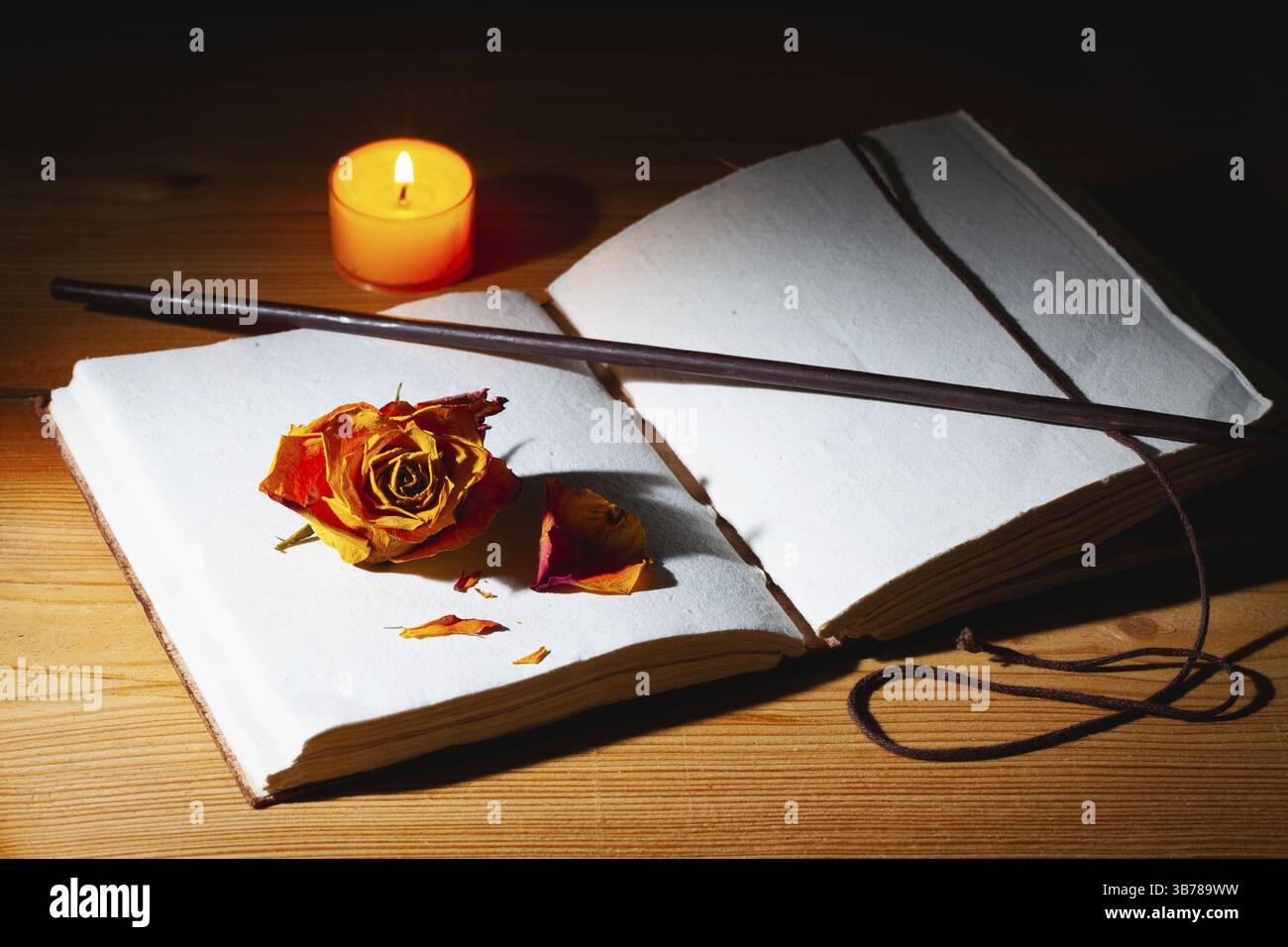 Image de livre magique ouvert, baguette et bougie allumée sur la table en bois dans la pièce sombre Banque D'Images
