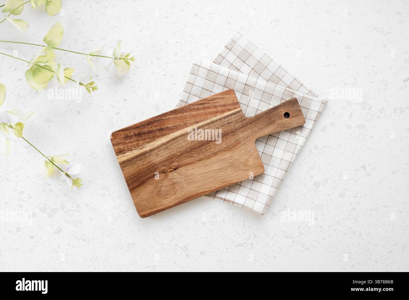 Planche à découper vue de dessus, plateau en bois de cuisine décoré avec un tissu plié à carreaux sur une table blanche.toile de fond de nourriture. Videz la vaisselle. Banque D'Images