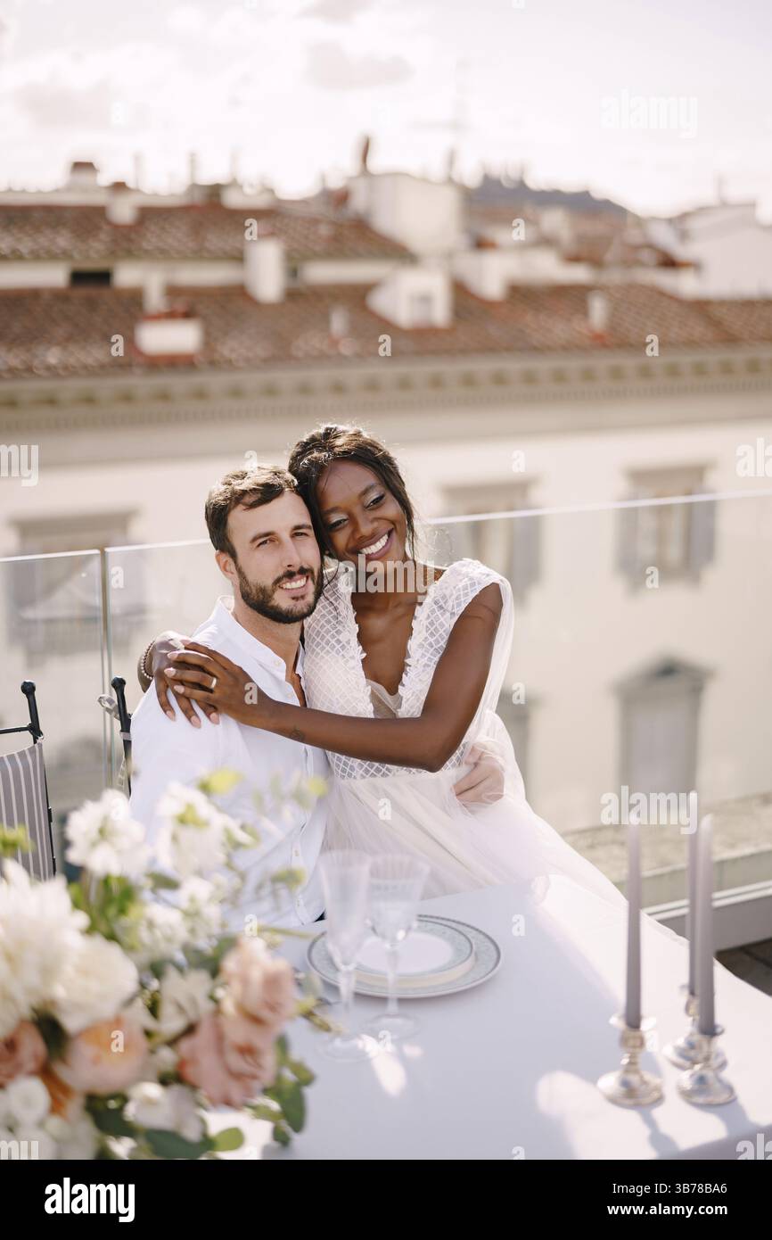 Couple de mariage interracial. Destination mariage beaux-arts à Florence, Italie. Mariée afro-américaine et mariée caucasienne sont assis sur le toit marié Banque D'Images