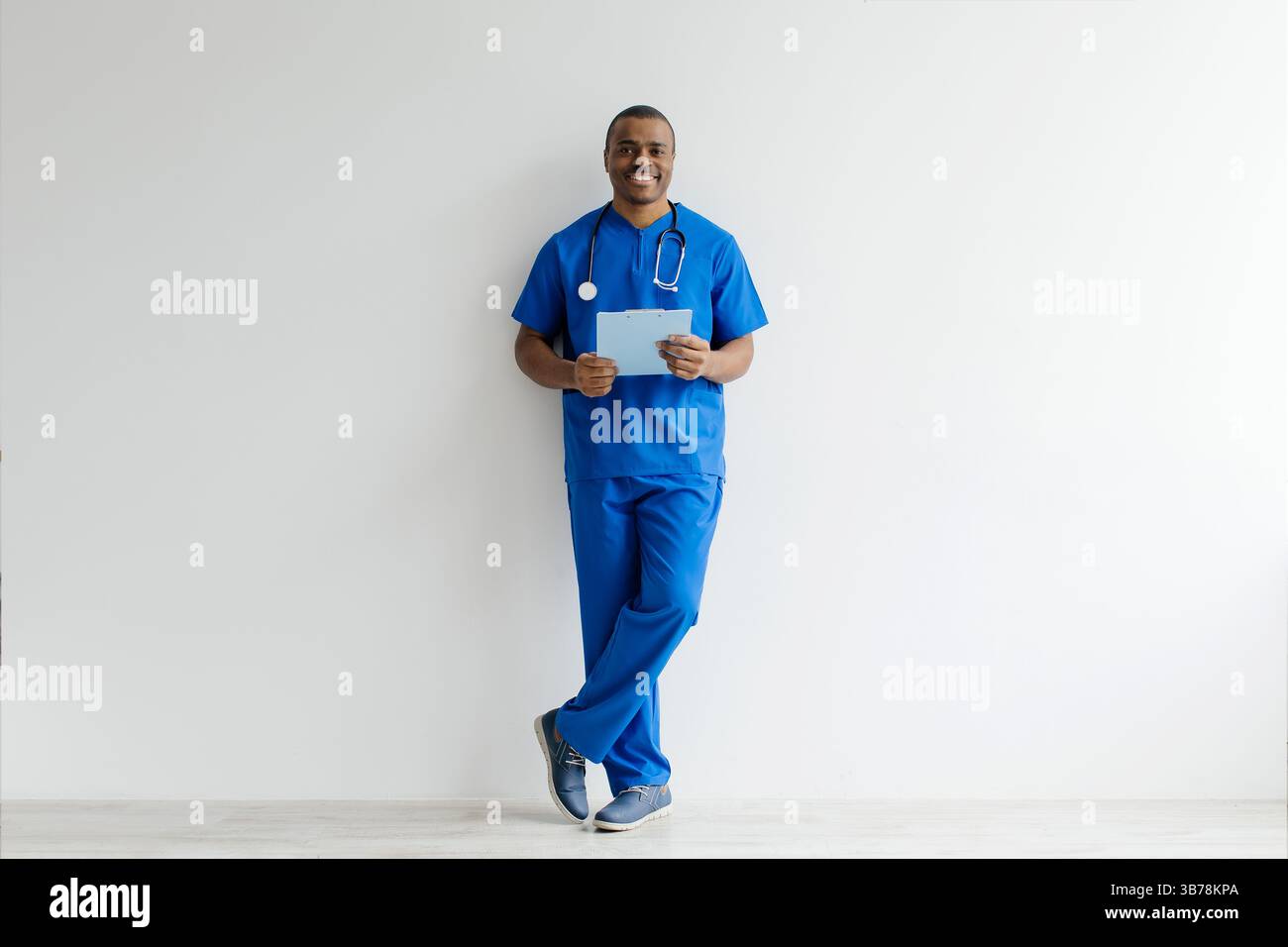 Sourire jeune Noir Docteur homme en uniforme avec presse-papiers dans les mains Banque D'Images