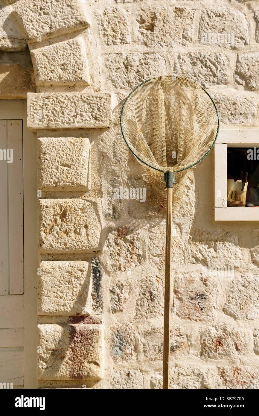 Filet de pêcheur sur fond de mur de pierre, lumière du soleil rugueuse Banque D'Images