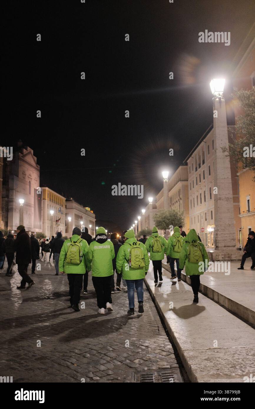 Jubilé bénévoles en vestes vert vif marchant et organisant dans le centre-ville de Rome la nuit pendant l'événement religieux catholique de l'année Sainte Italie. Photo de haute qualité Banque D'Images