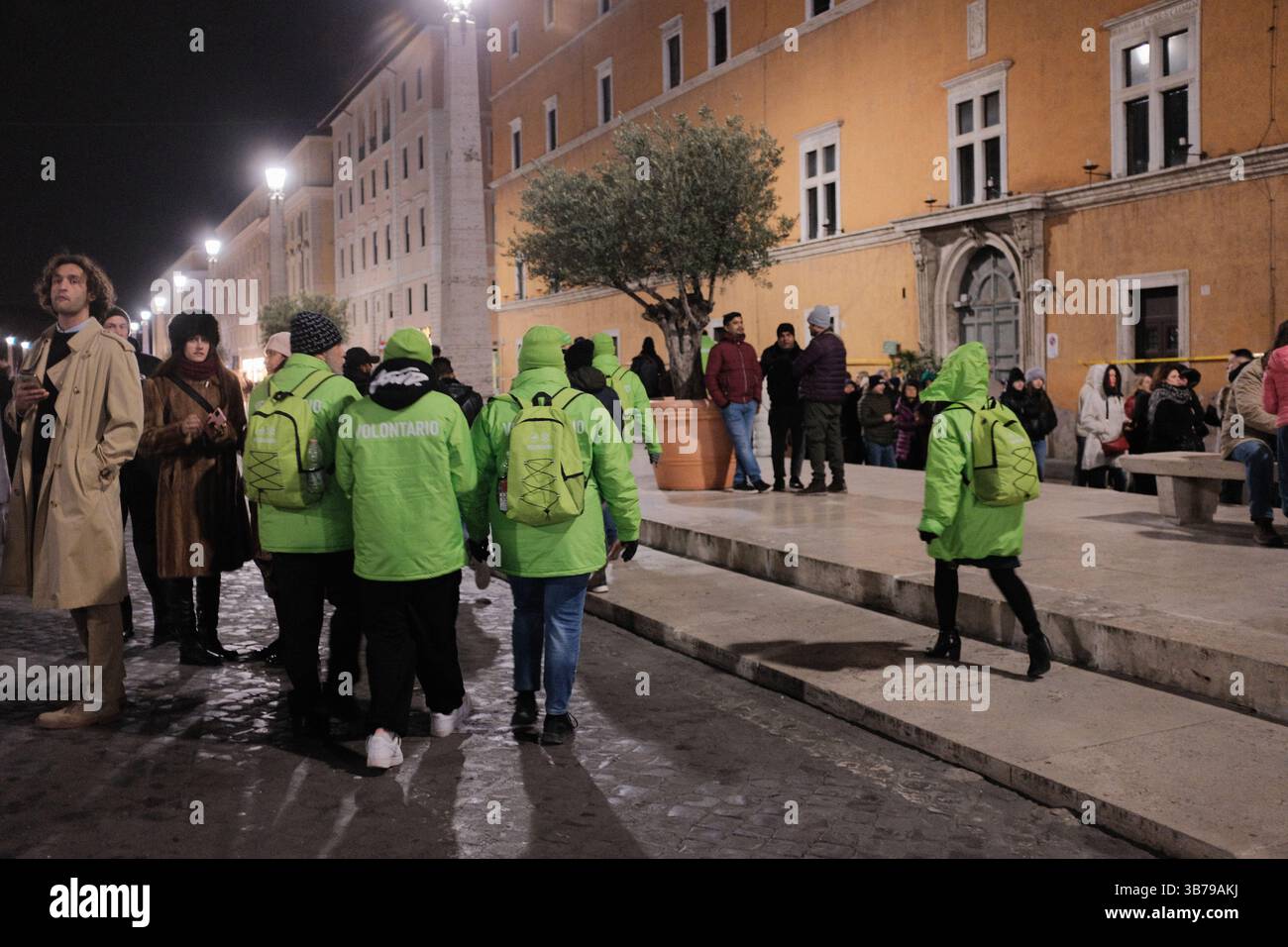 Jubilé bénévoles en vestes vert vif marchant et organisant dans le centre-ville de Rome la nuit pendant l'événement religieux catholique de l'année Sainte Italie. Photo de haute qualité Banque D'Images