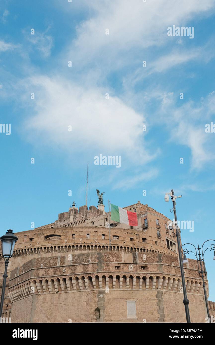 Château Sant Angelo avec drapeaux italiens agitant sur le dessus sous le ciel bleu à Rome vu d'en bas montrant forteresse circulaire et monument historique. Banque D'Images