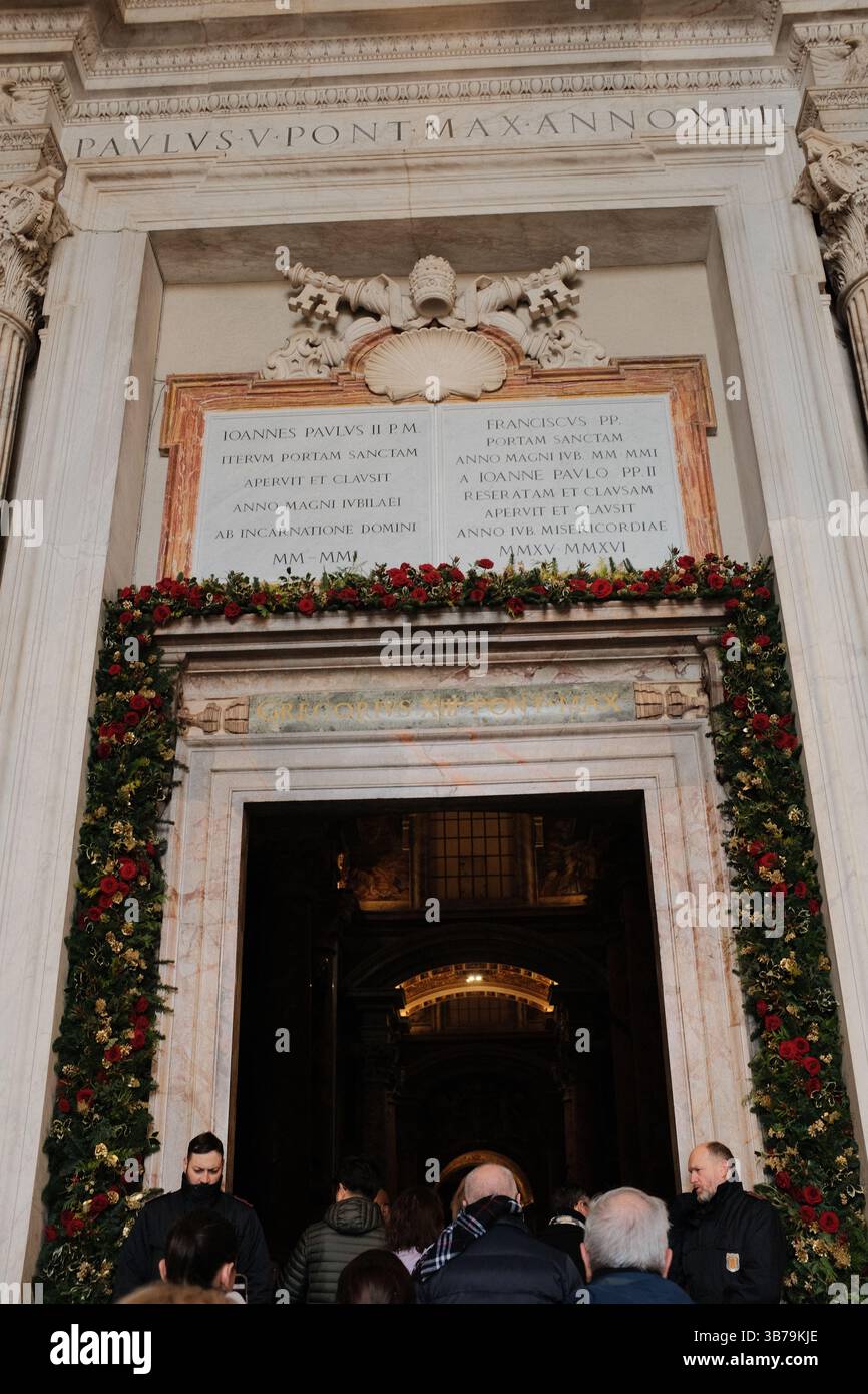 Entrée de la basilique Saint-Pierre décorée de guirlandes et de couronnes festives pour la saison de Noël, tandis que les visiteurs entrent dans le monument de la Cité du Vatican pour célébrer et adorer la porte sainte. Photo de haute qualité Banque D'Images
