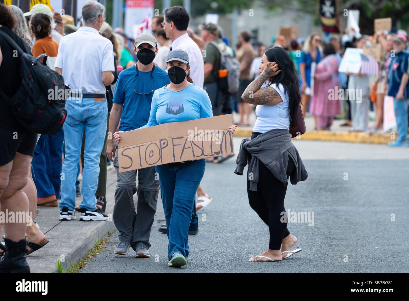 Honolulu, Hawaï, États-Unis – 5 février 2025 : Deux manifestants masqués portent une bannière « Stop au fascisme » lors d'une manifestation anti-Trump au Capitole de l'État. Banque D'Images