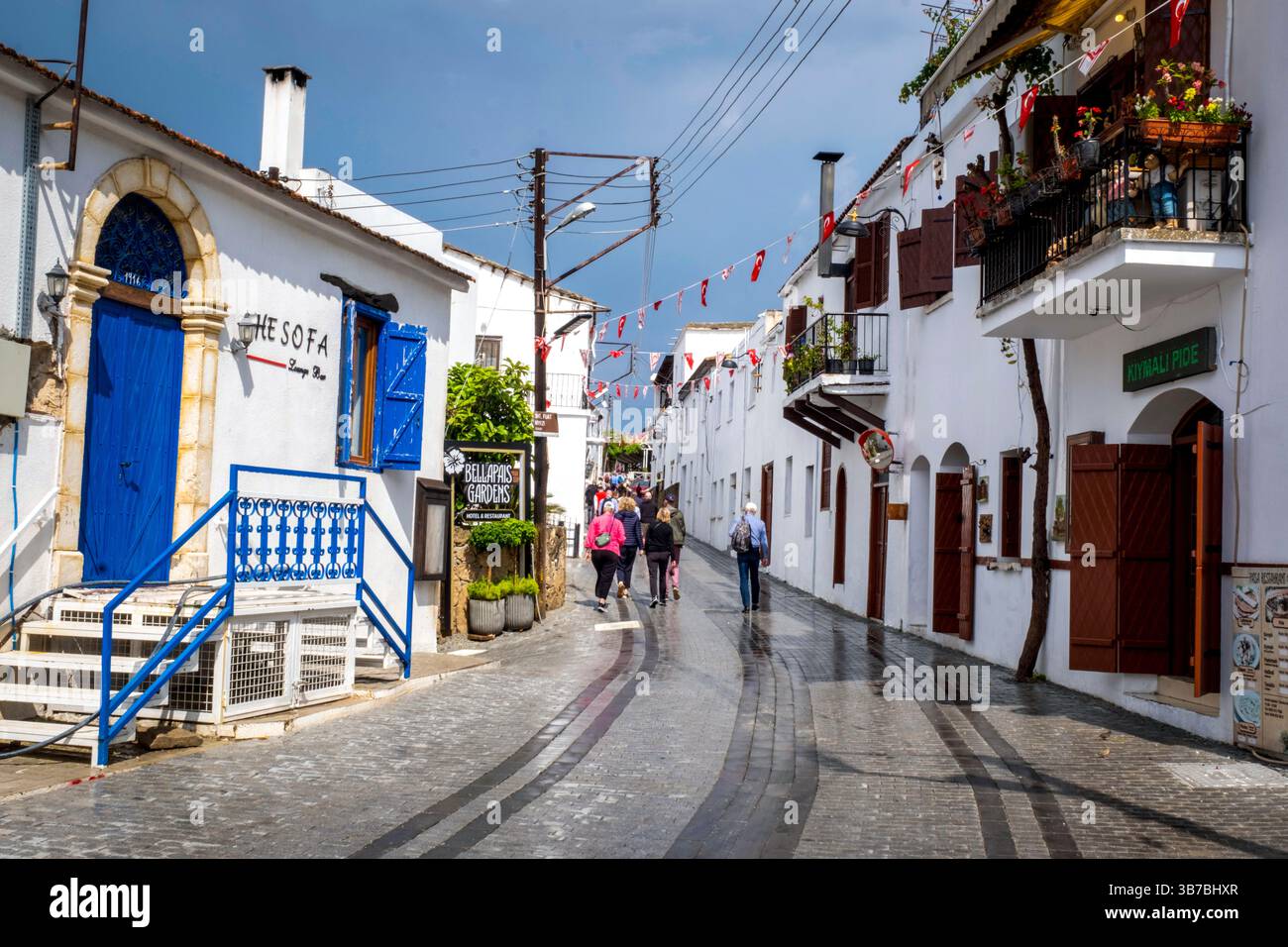 Touristes marchant le long de la rue principale, dans le village de Bellapais après une forte averse de pluie, Kyrenia / Girne, TRNC, Chypre du Nord Banque D'Images