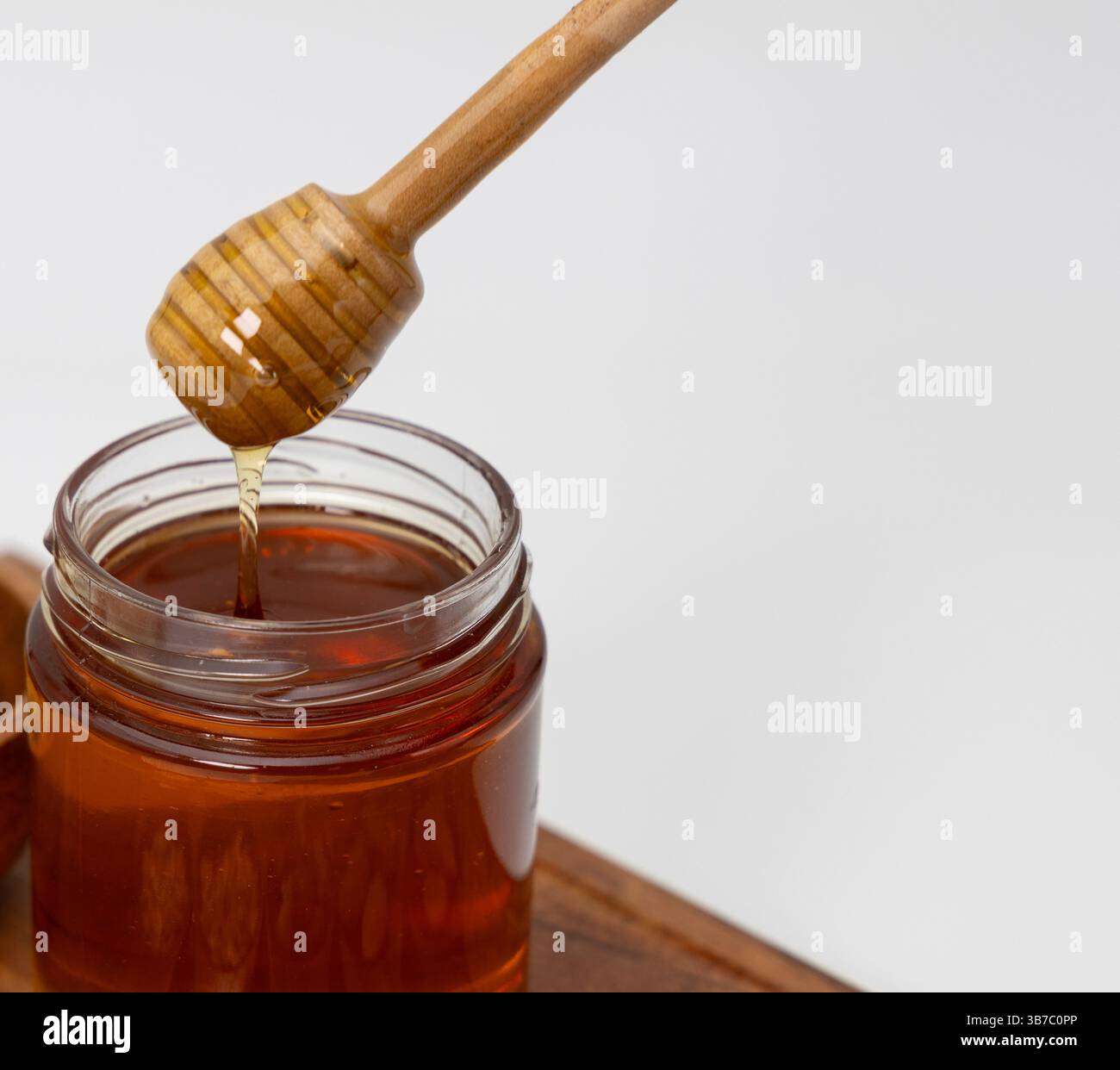 Miel s'égouttant de la trempette de miel dans un pot de miel Banque D'Images