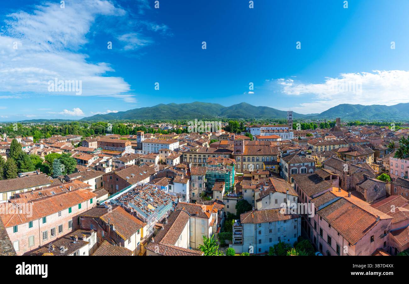 Vue panoramique de Lucques, Italie, avec des toits en briques rouges et des églises historiques vues d'en haut. Les collines et les montagnes toscanes forment un magnifique arrière-plan estival Banque D'Images