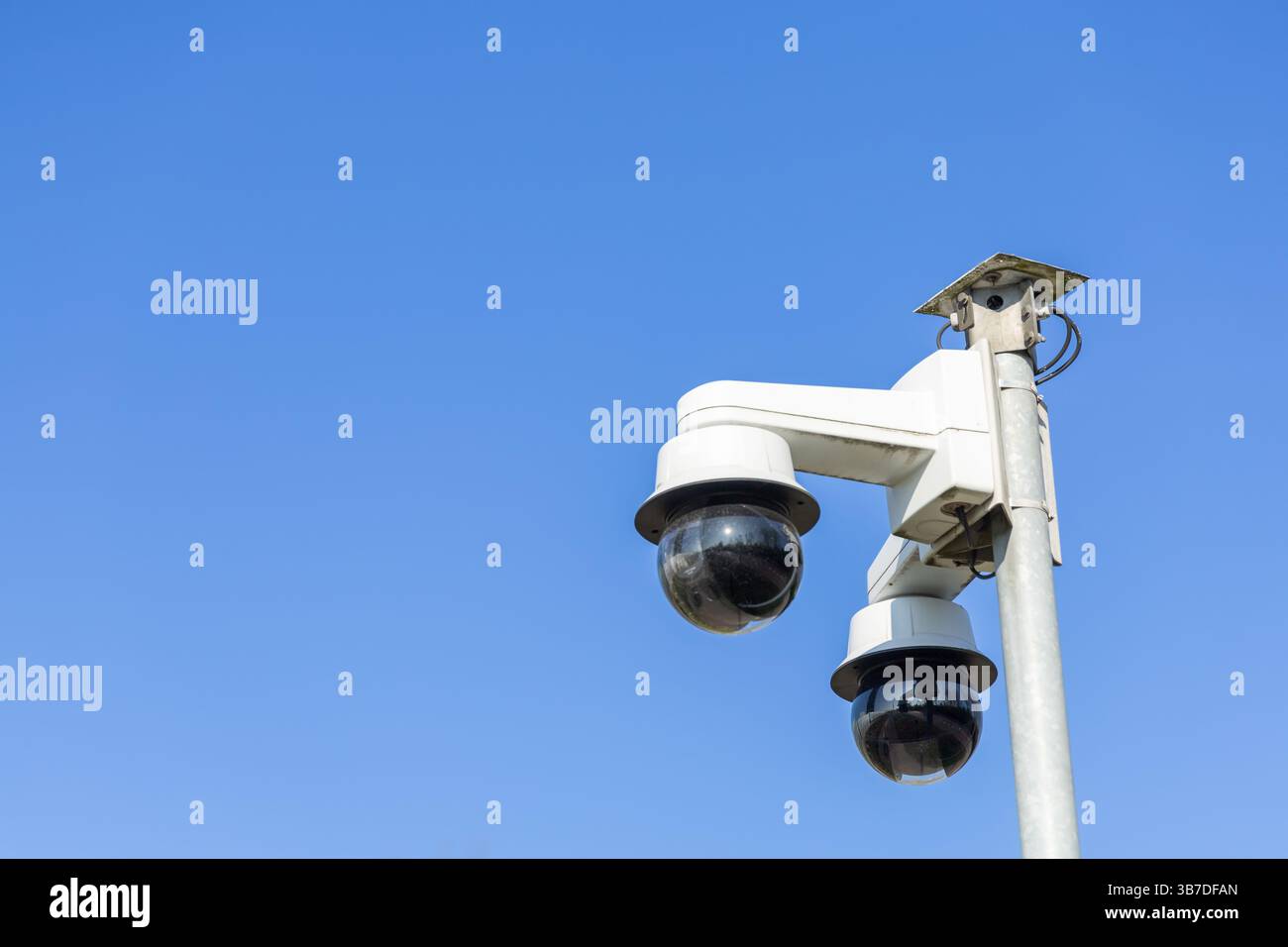 Deux caméras de sécurité sont montées sur un poteau, surveillant la zone sous un ciel dégagé Banque D'Images
