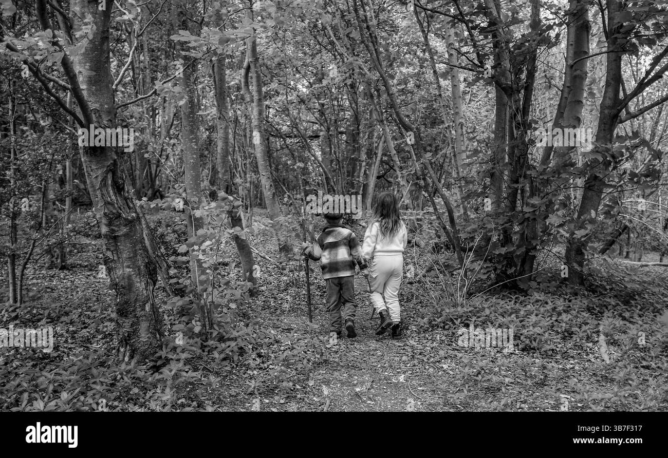 Garçon et fille marchant à travers les bois de Stanmer Park sur un chemin à Spring Brighton UK : crédit Simon Dack Banque D'Images