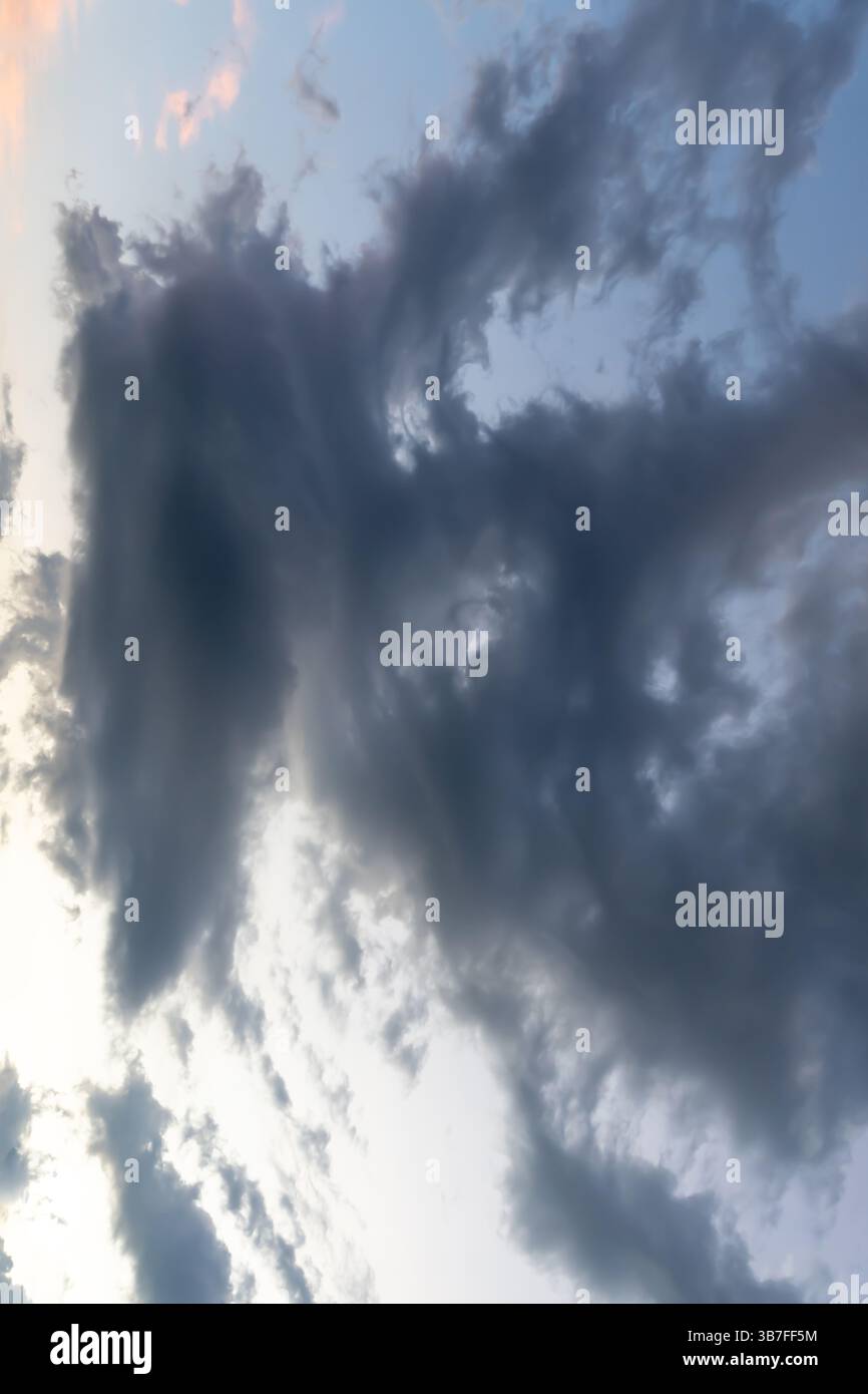 Vue à angle bas du ciel sombre avec une forme étrange de nuages noirs moelleux le matin ou le soir tandis que le coucher du soleil ou le lever du soleil est utilisé comme fond naturel t Banque D'Images