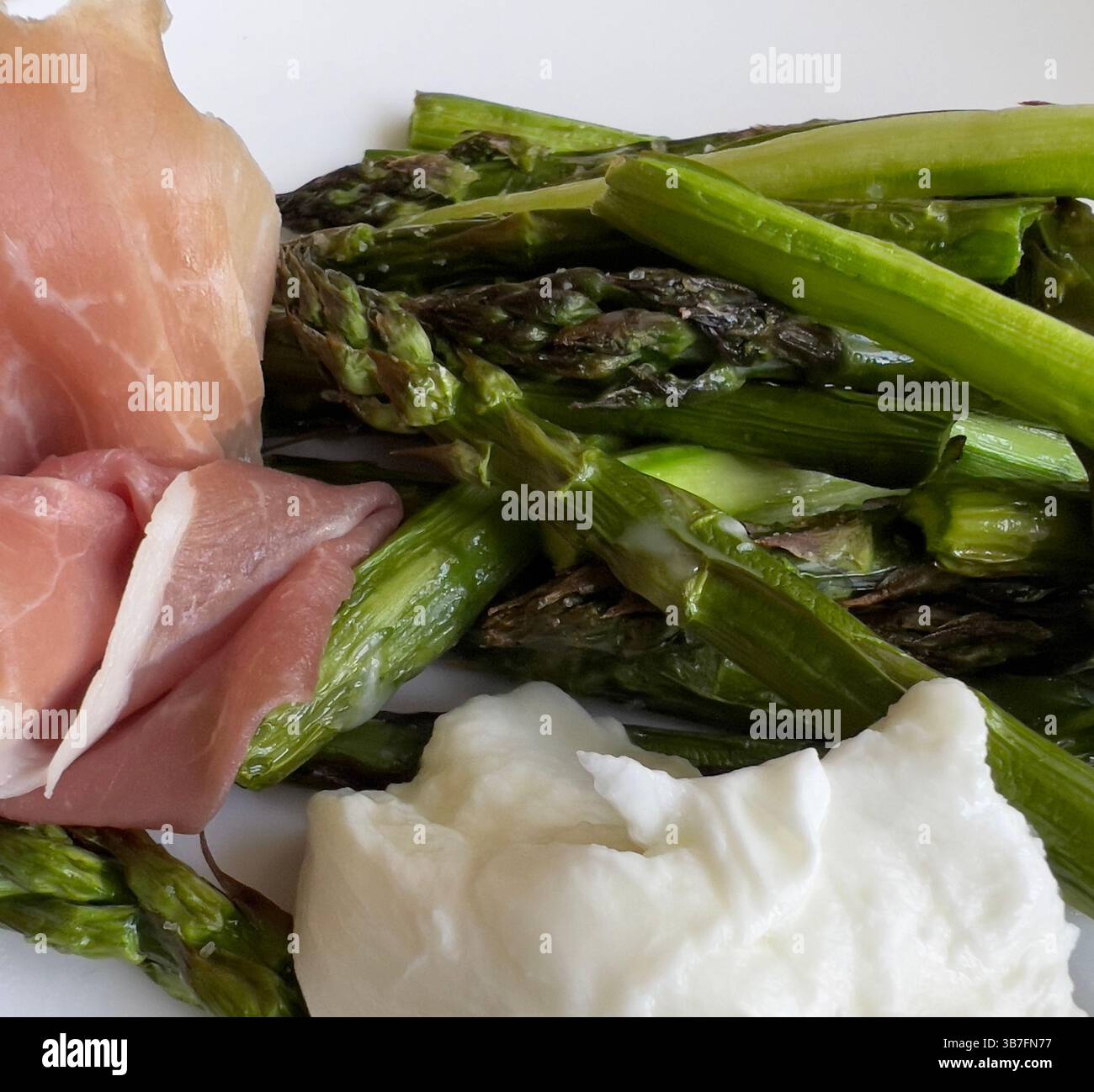 Gros plan de lances d'asperges vertes grillées servies sur une assiette blanche propre. Plat de légumes de saison sain - Image de stock capturée avec un smartphone