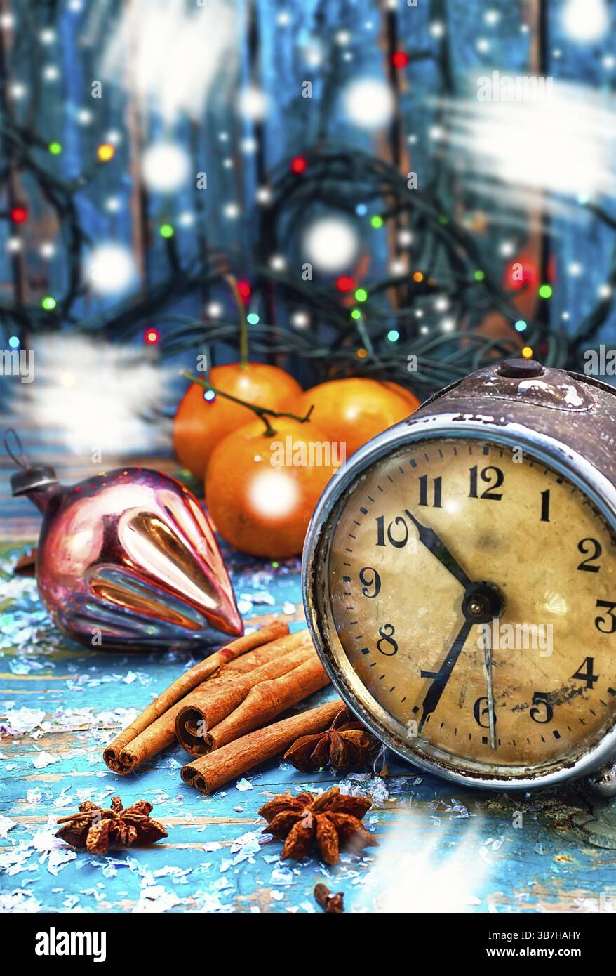 Réveil à l'ancienne, épices et mandarines sur fond de guirlandes de Noël.neige peinte Banque D'Images