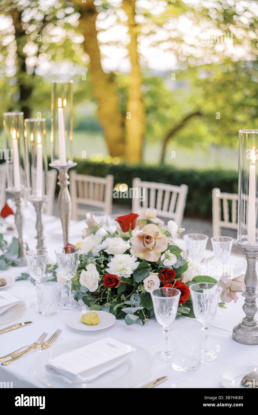 Bouquet coloré de fleurs se dresse sur une table de fête près de bougies allumées. Banque D'Images