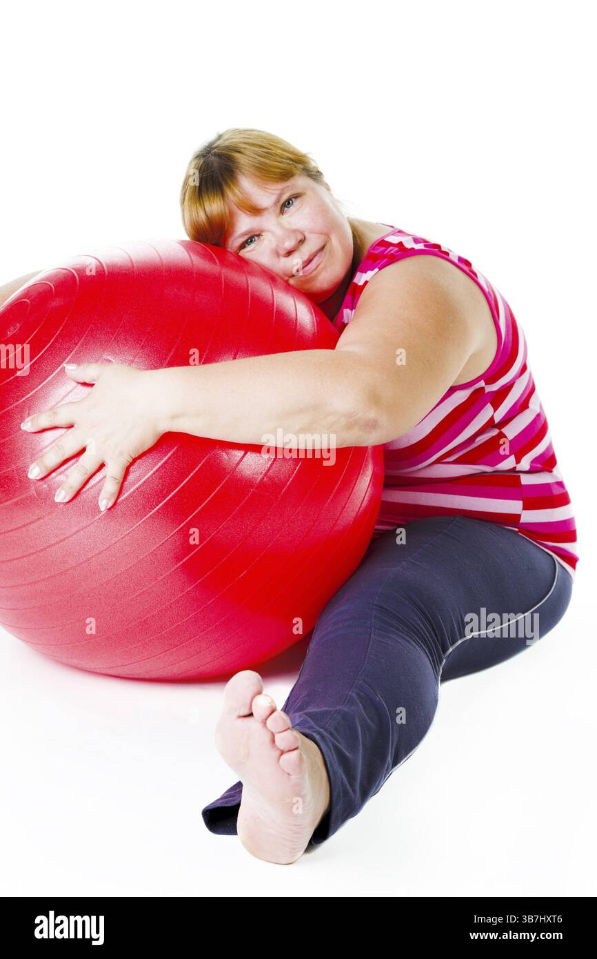 Grosse femme fatiguée avec une grosse balle de gymnastique rouge Banque D'Images