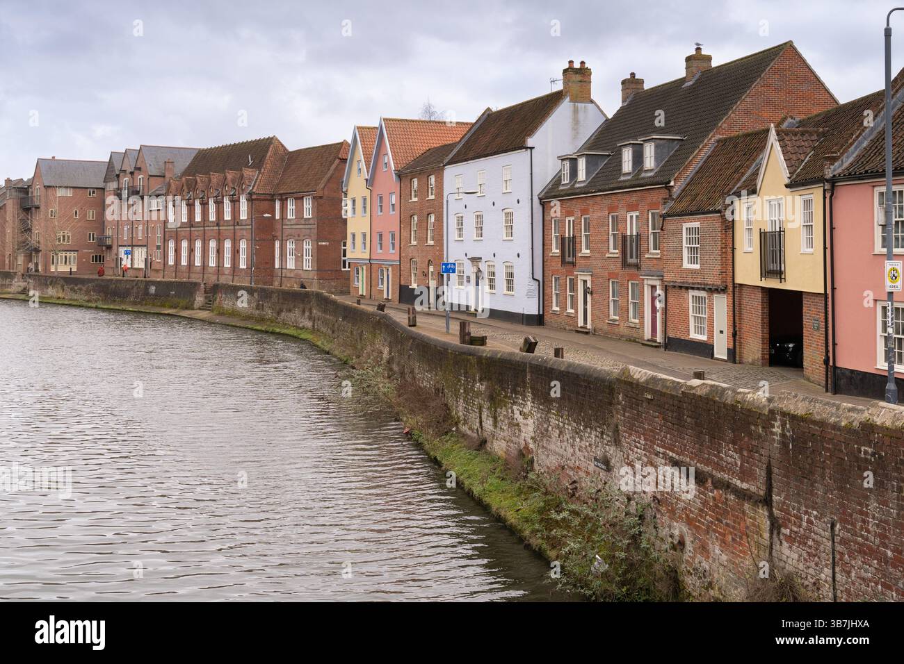 Les gens se promènent le long de la rivière Wensum à Norwich, au Royaume-Uni, en profitant de la vue sur les bâtiments historiques sur la rive. Banque D'Images