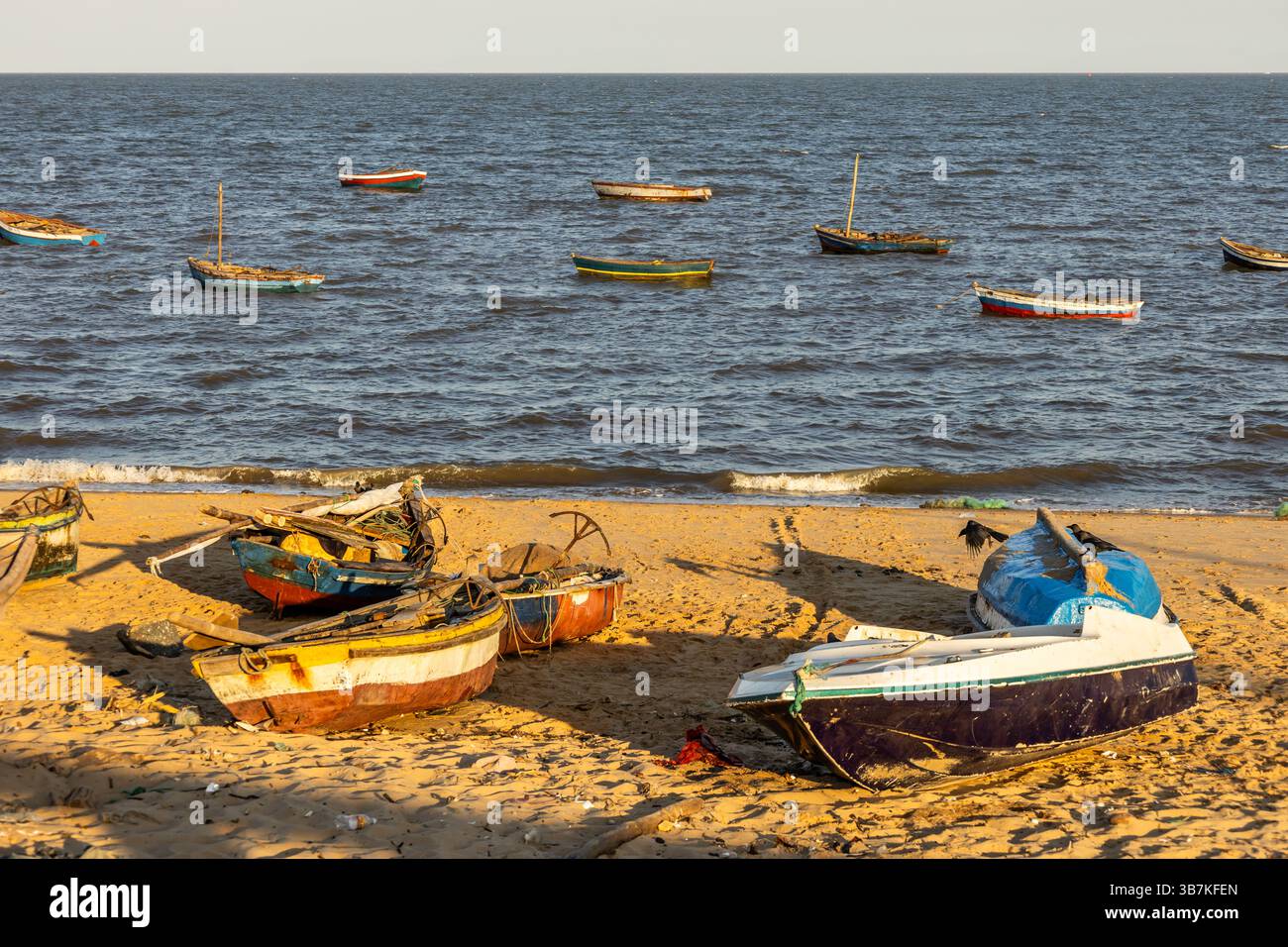 Bateaux de pêche échoués sur la plage de sable en fin d'après-midi soleil sur un petit marché aux poissons au Mozambique après une longue journée de travail Banque D'Images