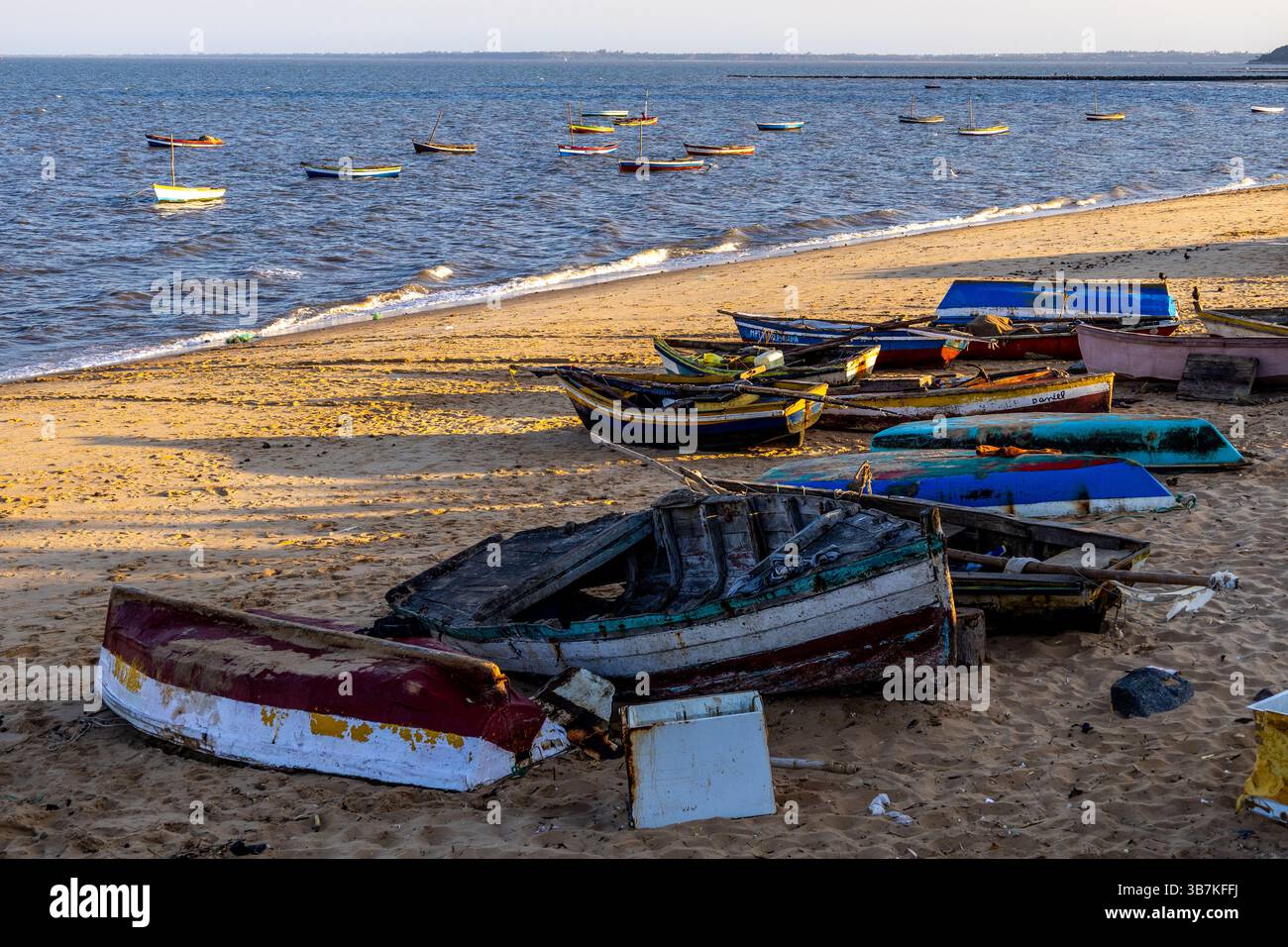 Bateaux de pêche échoués sur la plage de sable en fin d'après-midi soleil sur un petit marché aux poissons au Mozambique après une longue journée de travail Banque D'Images