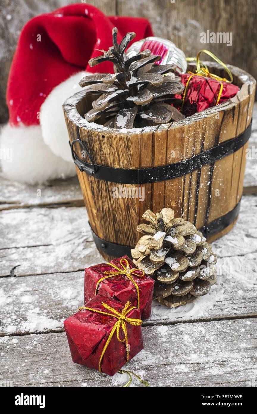 Baignoire en bois remplie de pommes de pin et d'ornements de Noël sur fond de neige Banque D'Images