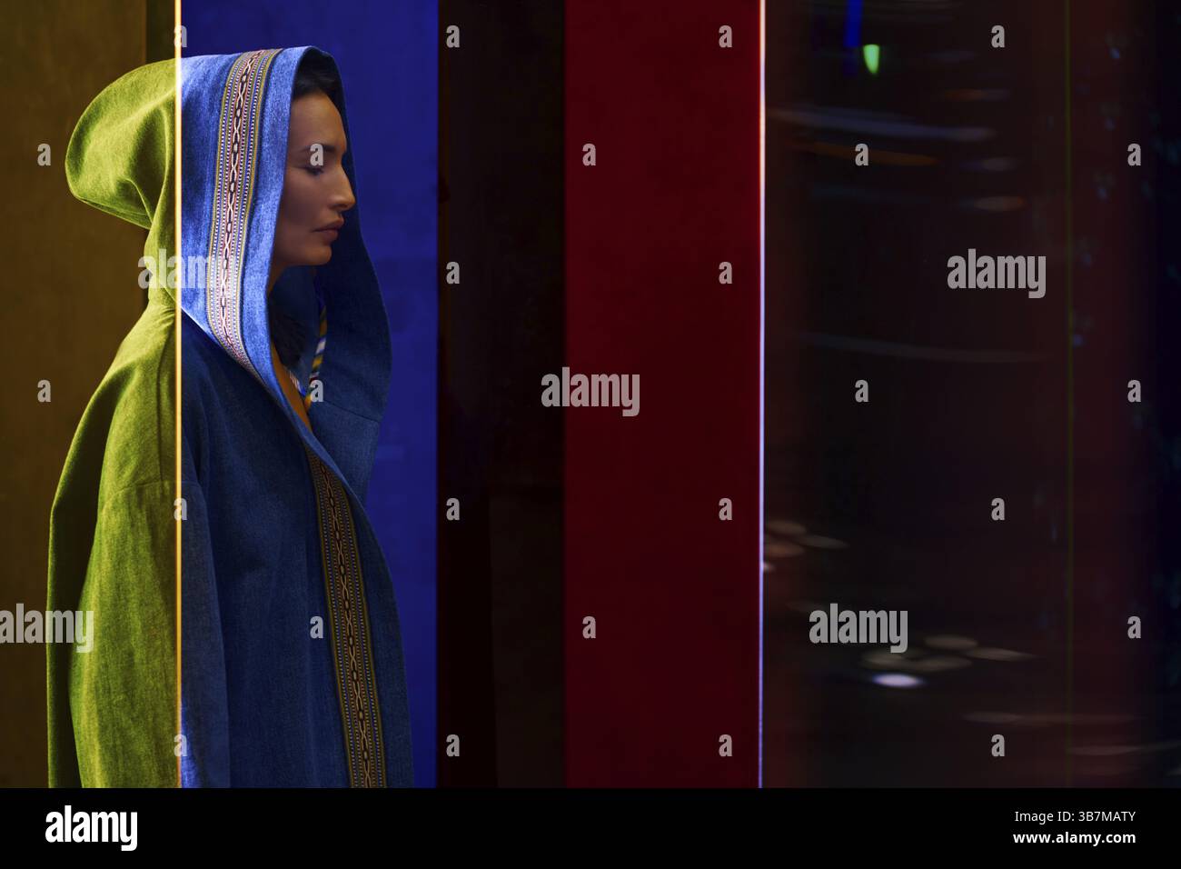 Femme en robe patchwork asiatique traditionnelle colorée debout derrière le verre coloré Banque D'Images