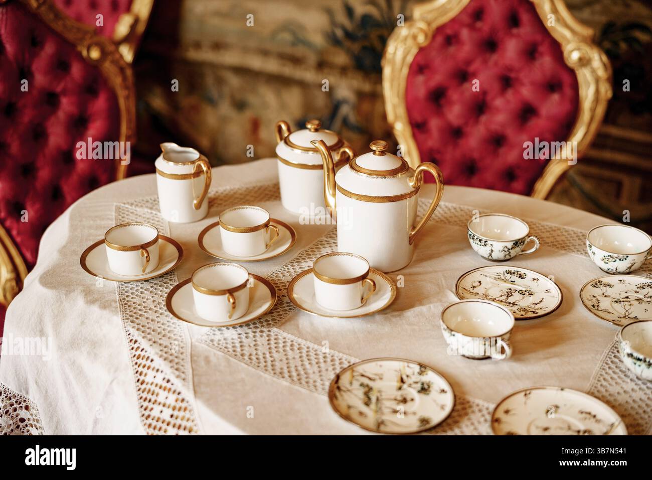 Gros plan sur une table en dentelle blanche avec chaises rouges en peluche. Banque D'Images