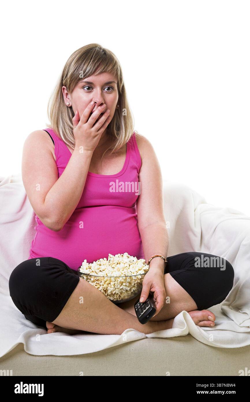 Belle grosse jeune femme regardant la télé et mangeant du pop-corn Banque D'Images