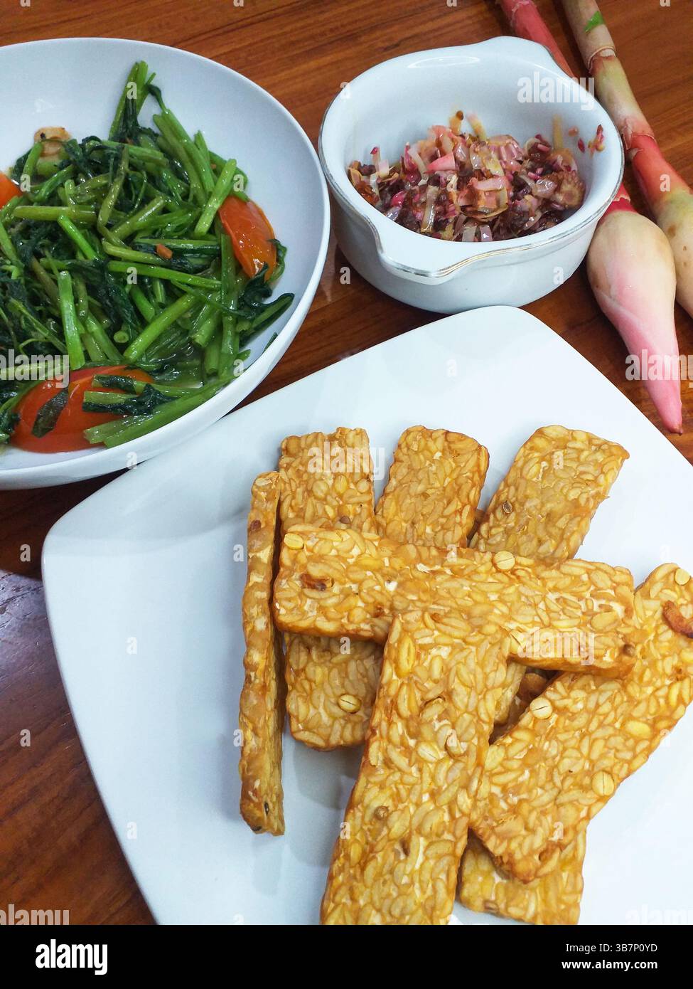 Tempe goreng avec tumis kangkung et sambal kecombrang, nourriture indonésienne servie sur un lit de riz blanc cuit à la vapeur sur une assiette blanche carrée Banque D'Images