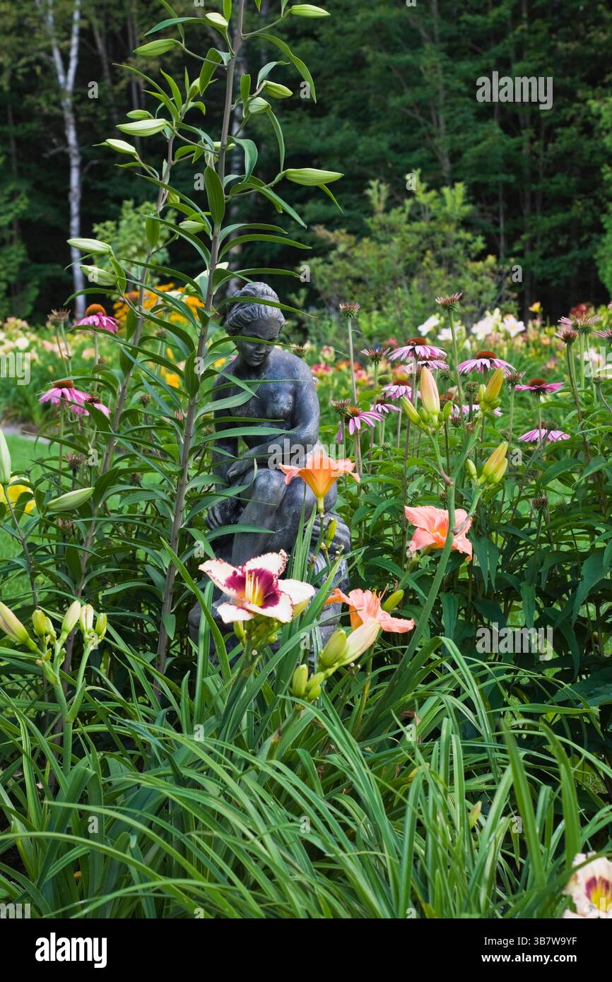 Frontière avec mélange Hemerocallis - fleurs Dayliliy et béton coulé statue 'la Monica' et violet Echinacea purpurea - Coneflowers dans le comte de cour Banque D'Images
