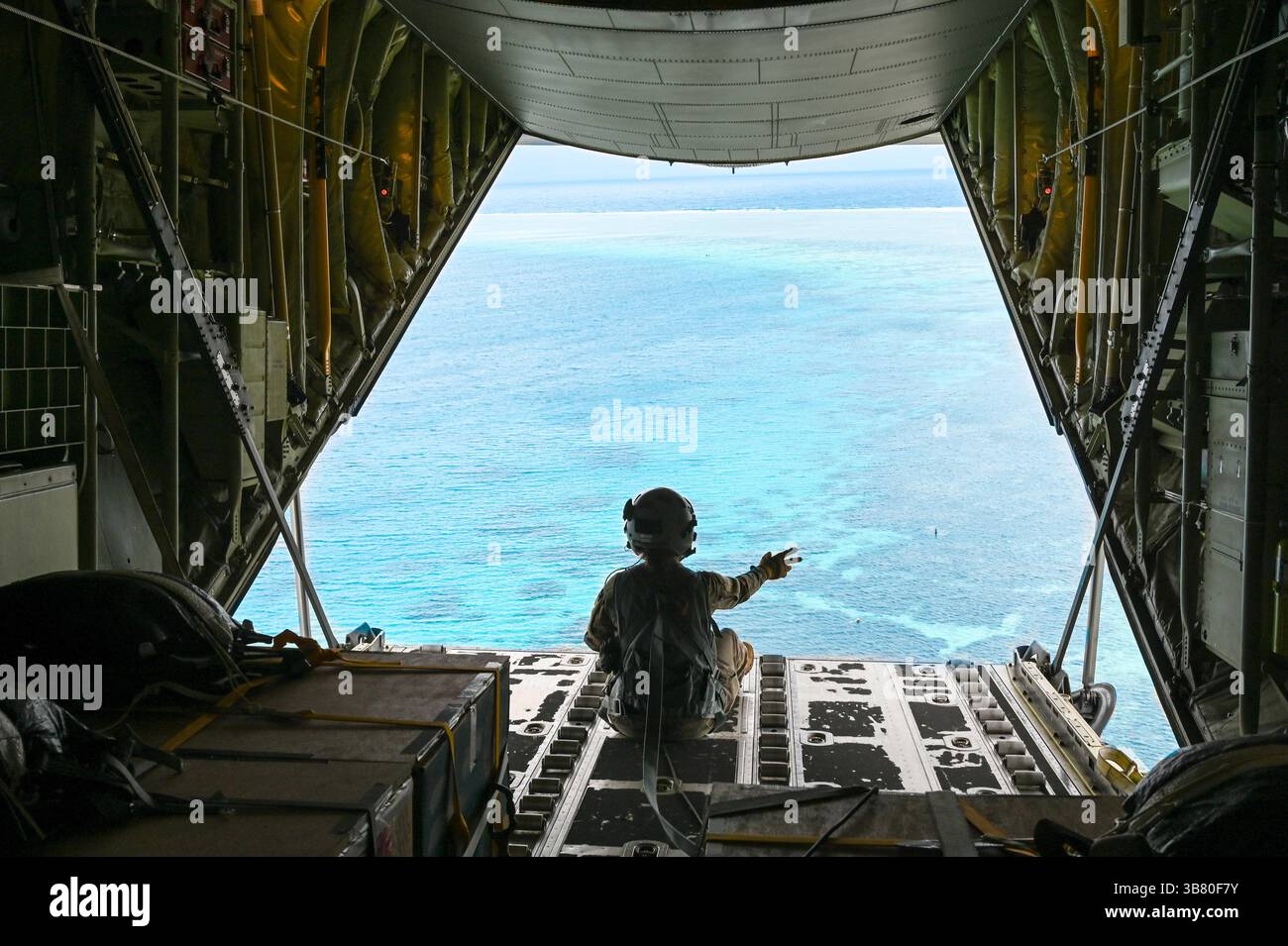 4 décembre 2023, Nama, Upper Mortlock Islands, État de Chuuk, États fédérés de Micronésie : Megan Irvin, maître de chargement de l'US Air Force Senior Airman, vagues après avoir largué des faisceaux humanitaires en parachute vers une lagune à partir d'un avion C-130J Super Hercules de l'US Air Force, lors de l'opération Christmas Drop, le 4 décembre 2023 à Nama, Îles de l'est, Micronésie. L’opération Christmas Drop est la plus ancienne mission humanitaire et de secours en cas de catastrophe, livrant 71 000 livres de nourriture, de cadeaux et de fournitures pour aider les communautés insulaires éloignées du Pacifique Sud. (Crédit image : © Sra Allison Martin/US Airforce/plane Banque D'Images