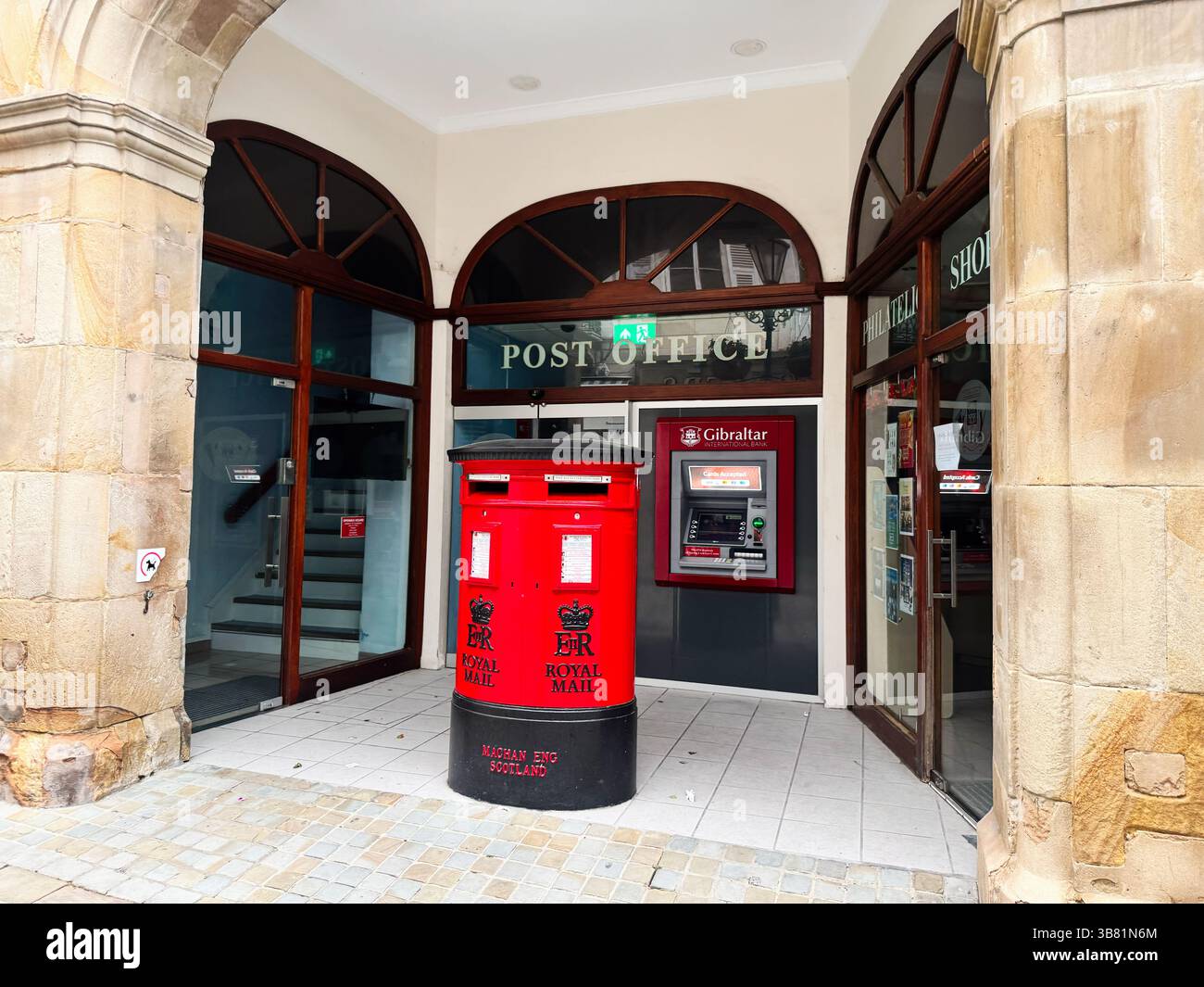 Gibraltar, Royaume-Uni - 1er mai 2025 : une boîte aux lettres rouge Royal mail et un distributeur automatique de billets devant le bureau de poste de Gibraltar Banque D'Images