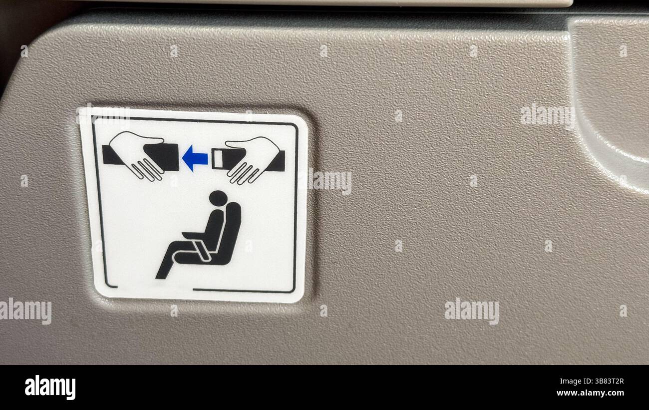 Panneau de sécurité sur le dossier de siège d'avion soulignant l'importance de la sécurité des ceintures de sécurité pour les passagers mis en évidence par de simples illustrations d'instructions. Banque D'Images
