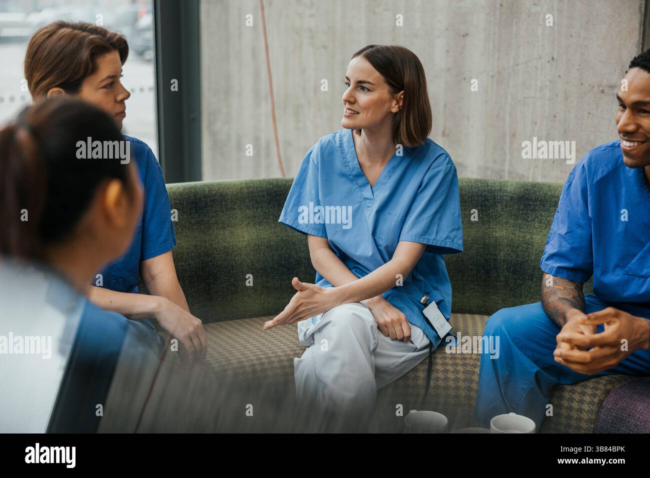 Infirmière discutant avec des collègues assis sur le canapé dans la clinique Banque D'Images