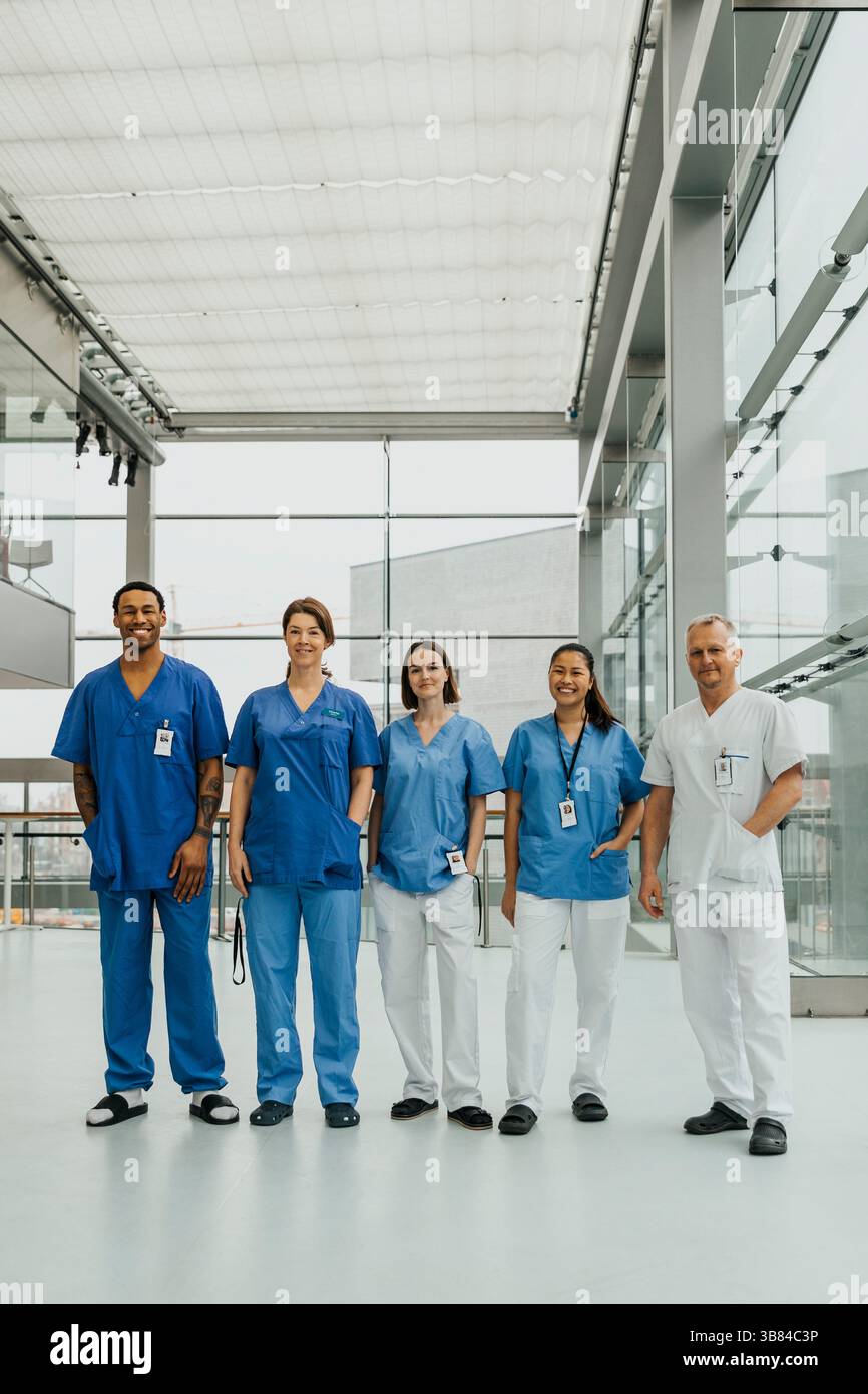 Portrait d'une équipe médicale masculine et féminine debout côte à côte dans le couloir de l'hôpital Banque D'Images