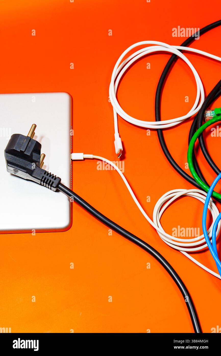 Un appareil électronique avec un tas de fils colorés sur une table orange. Banque D'Images