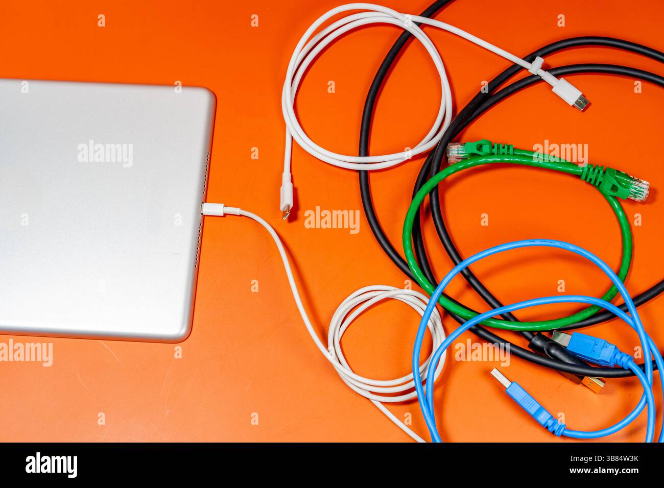 Un appareil électronique avec un tas de fils colorés sur une table orange. Banque D'Images