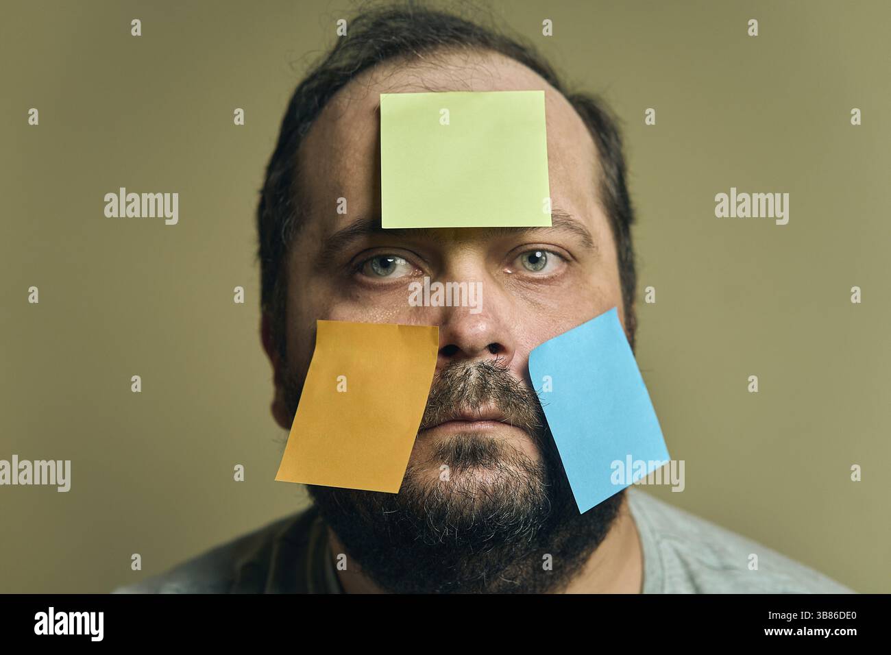 Portrait facial d'un homme avec une barbe regardant dans le cadre et recouvert d'autocollants en papier vierges Banque D'Images