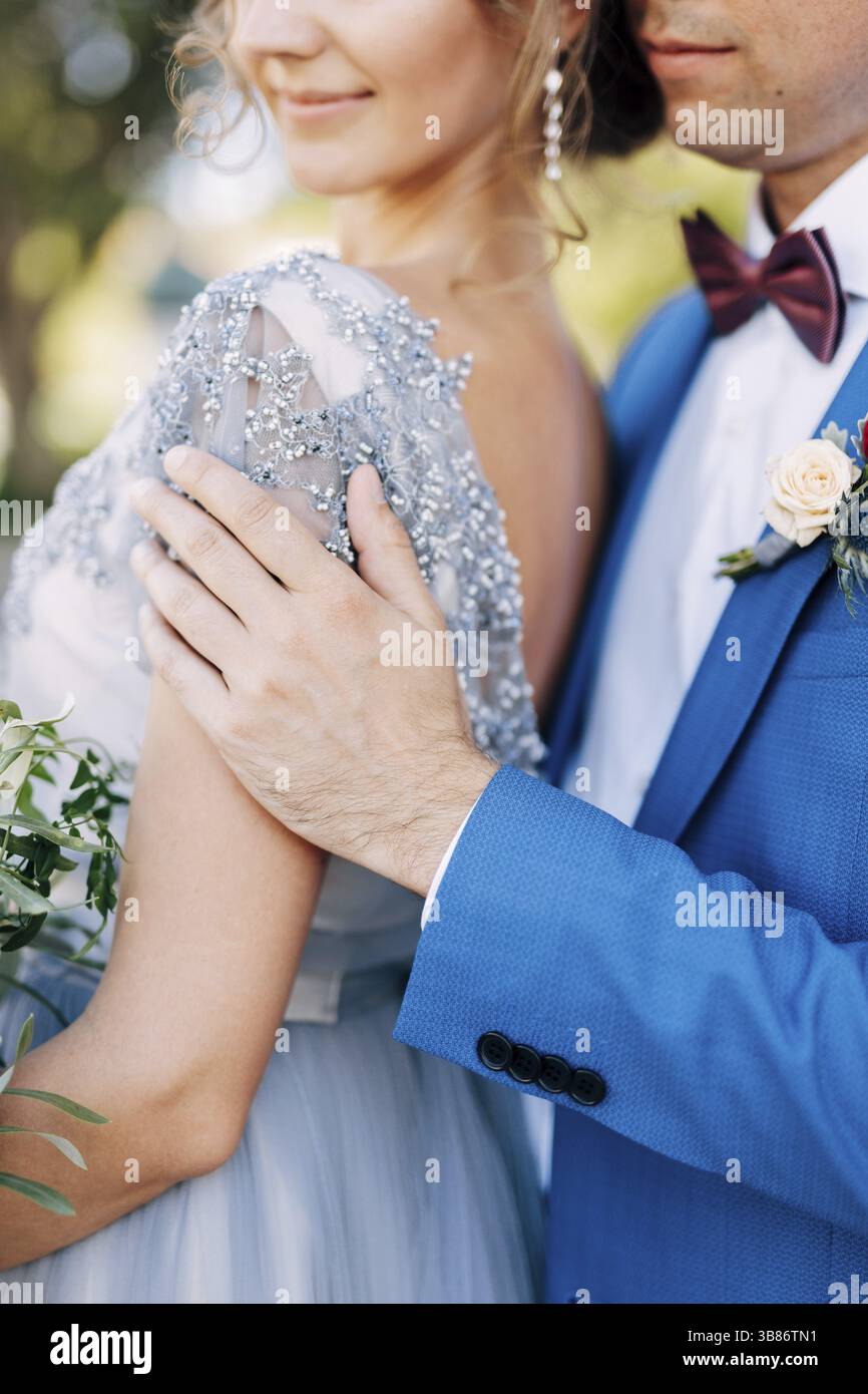 Kotor, Montenegro - 08.06.17: Marié dans un costume bleu hale la mariée avec un bouquet de fleurs par les épaules.Gros plan Banque D'Images