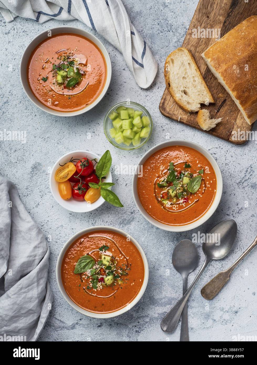 Soupe de gaspacho sur table en marbre blanc. Trois bols de purée espagnole traditionnelle à soupe froide gaspacho ou gazpacho sur fond gris clair ou marbre blanc Banque D'Images