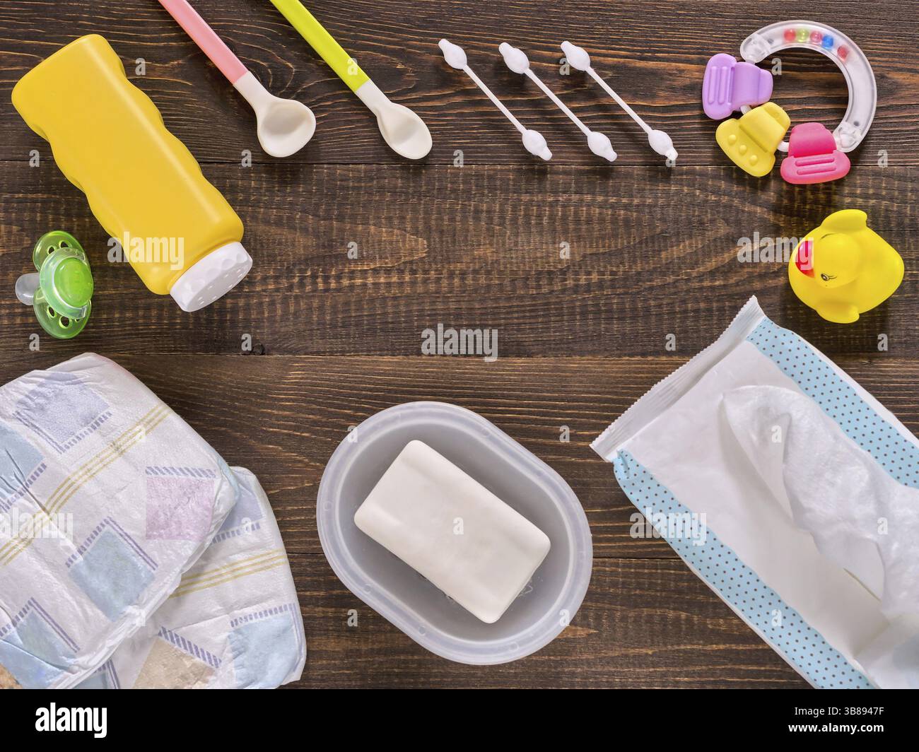 Les couches, les Japonais de lingettes, savon, poudre de bébé, tither, coton-tiges, cuillères, sucette et petit canard sur fond en bois brun foncé avec l'exemplaire de l'espace. Fla Banque D'Images