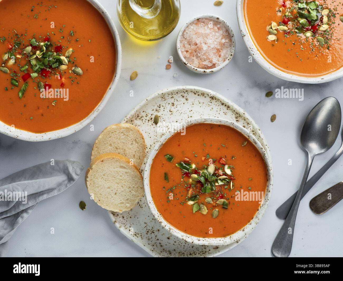 Soupe de gaspacho sur table en marbre blanc. Trois bols de purée espagnole traditionnelle à soupe froide gaspacho ou gazpacho sur fond gris clair ou marbre blanc Banque D'Images