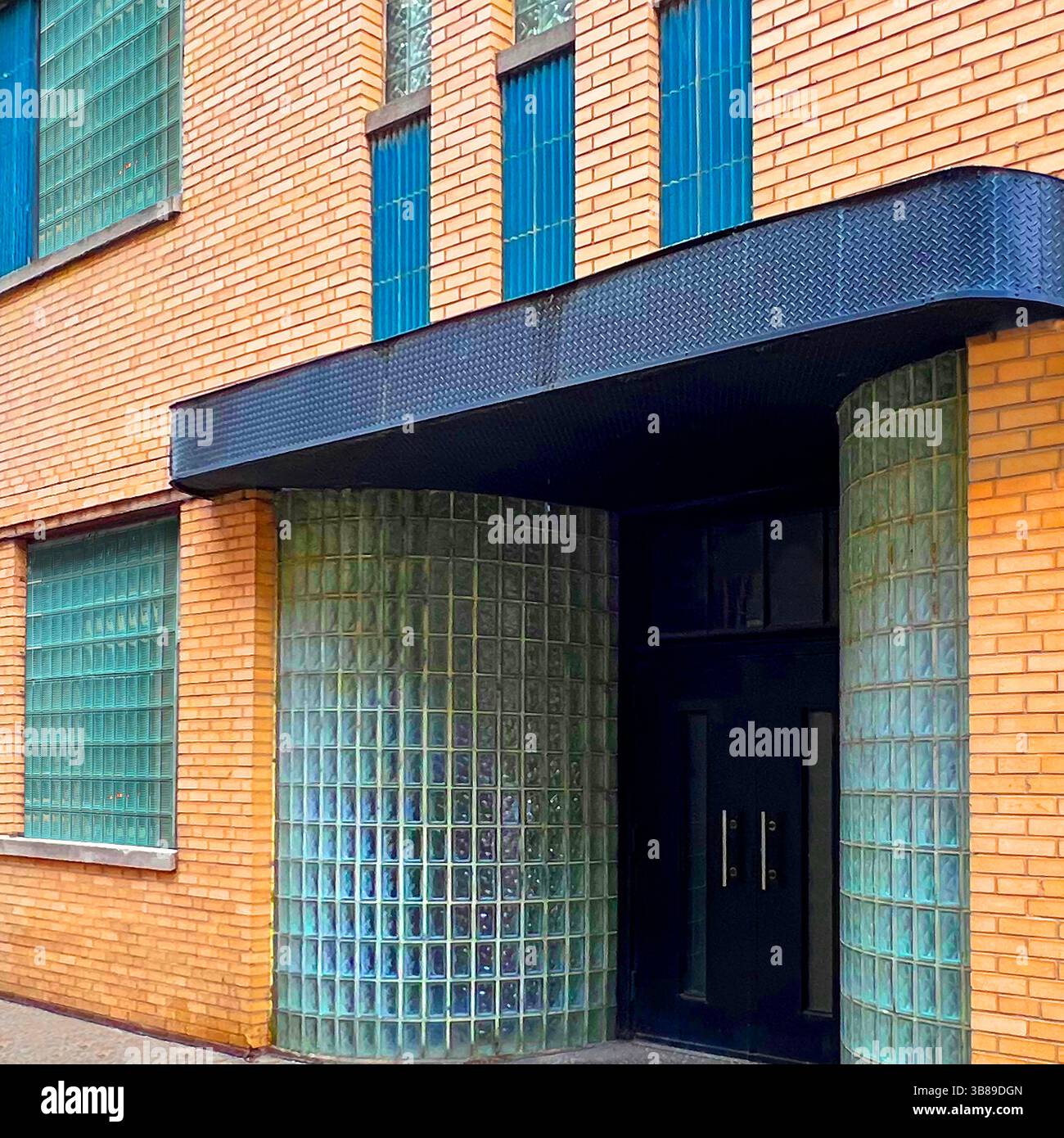 Streamline moderne Entrance avec des murs en blocs de verre incurvés et des accents verticaux de carreaux bleus sur une façade en briques jaunes à Chicago Banque D'Images