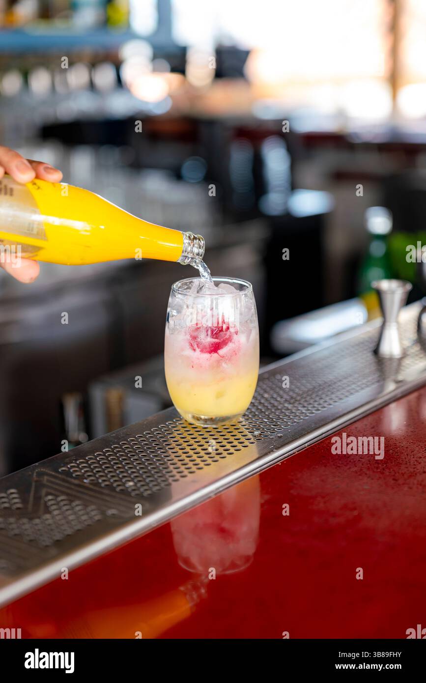 Midi dans un bar à Carthagène, en Colombie, un cocktail tropical vibrant avec de la glace, des agrumes et du sirop rouge est fraîchement versé et mélangé. Banque D'Images