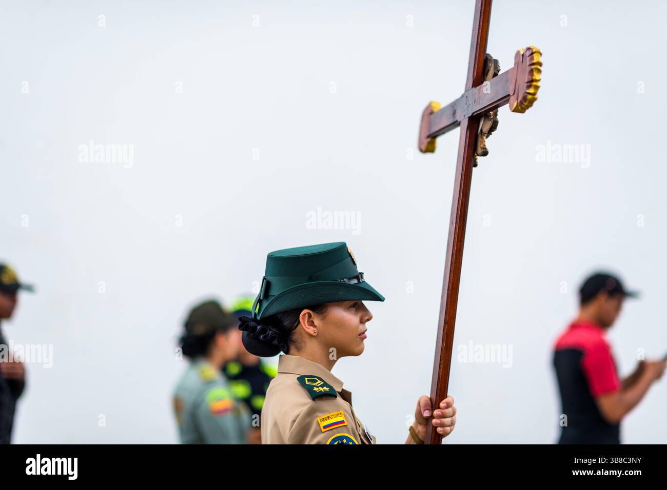 Un membre de la police nationale colombienne porte une croix alors qu'elle marche dans un cortège pendant les célébrations de la semaine Sainte à Mompox, en Colombie. Banque D'Images