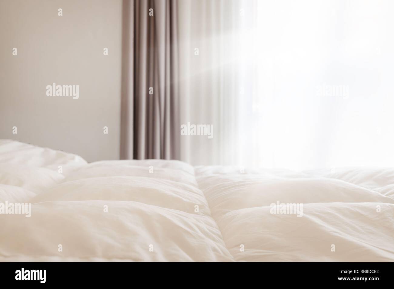 Chambre lumineuse avec literie blanche douce et rideaux Banque D'Images
