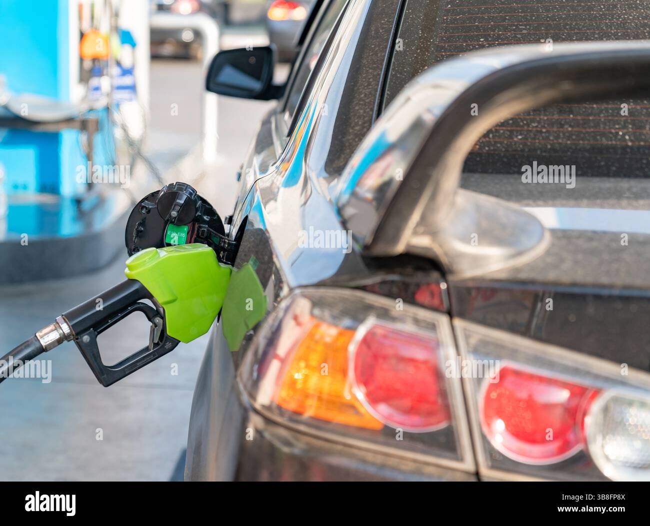 Gros plan d'une buse de pompe à carburant remplissant le réservoir d'une voiture, montrant le lien entre le véhicule et la source de carburant. Banque D'Images