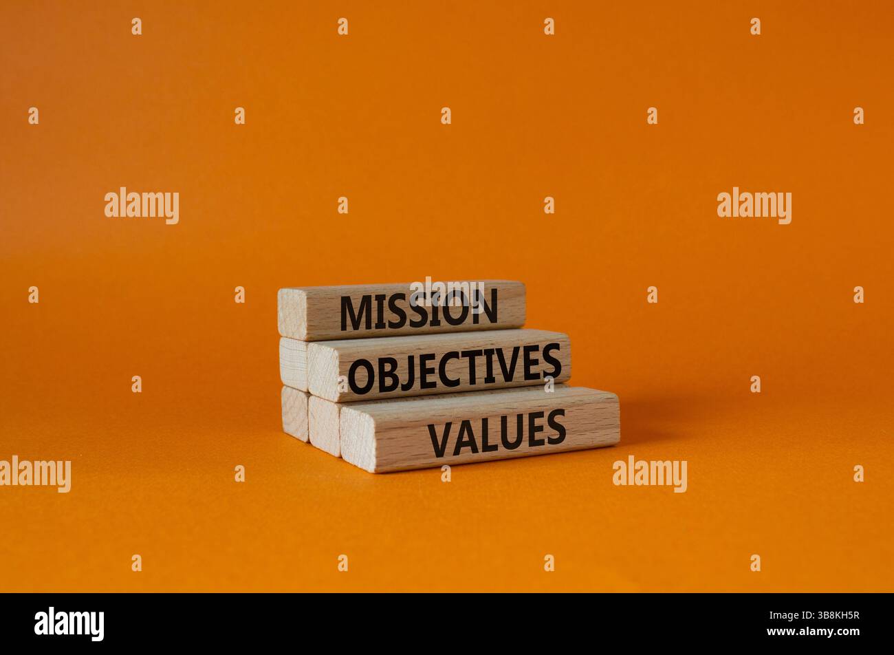 Symbole des valeurs des objectifs de mission. Mots conceptuels objectifs de mission valeurs sur blocs de bois. Beau fond orange. Affaires et Mission objectiv Banque D'Images