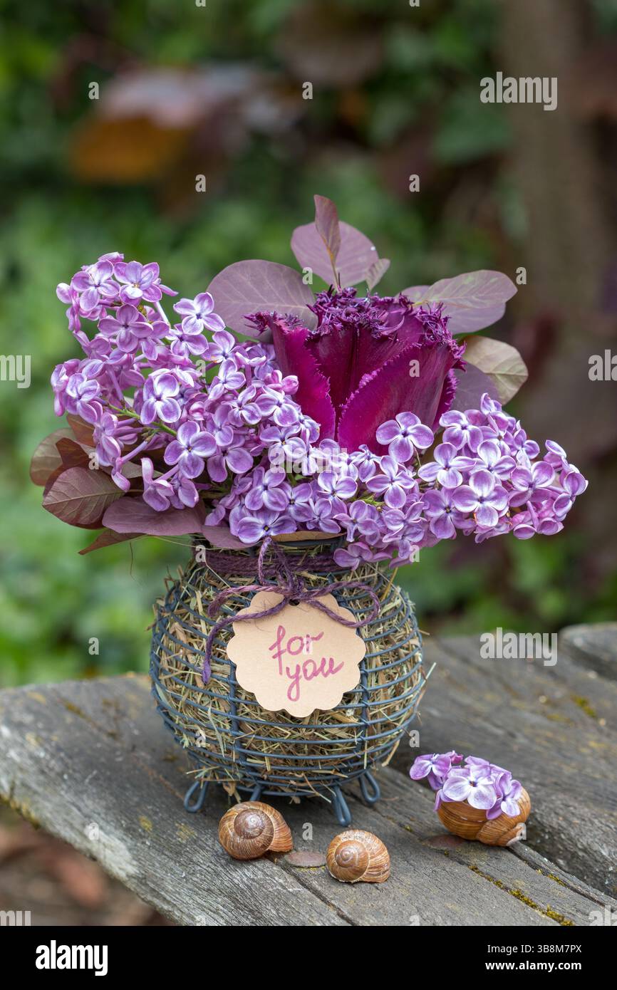 bouquet de tulipes violettes, fleurs de lilas et branches d'arbre à fumée dans un panier Banque D'Images