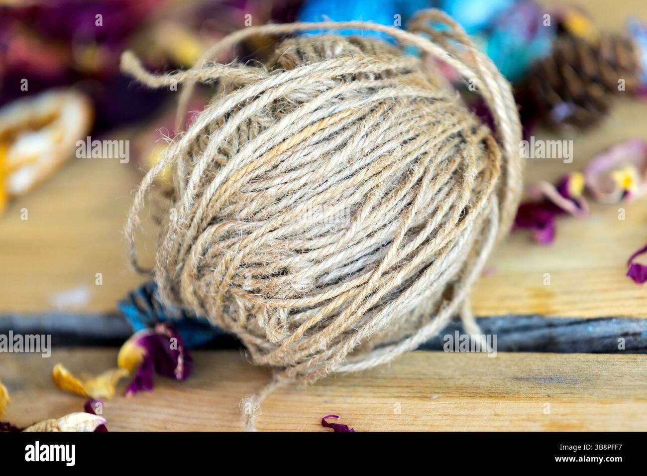 Gros rouleau de ficelle de jute brune pour l'artisanat couché sur une table en bois. Loisirs et thème des matériaux d'artisanat. Banque D'Images